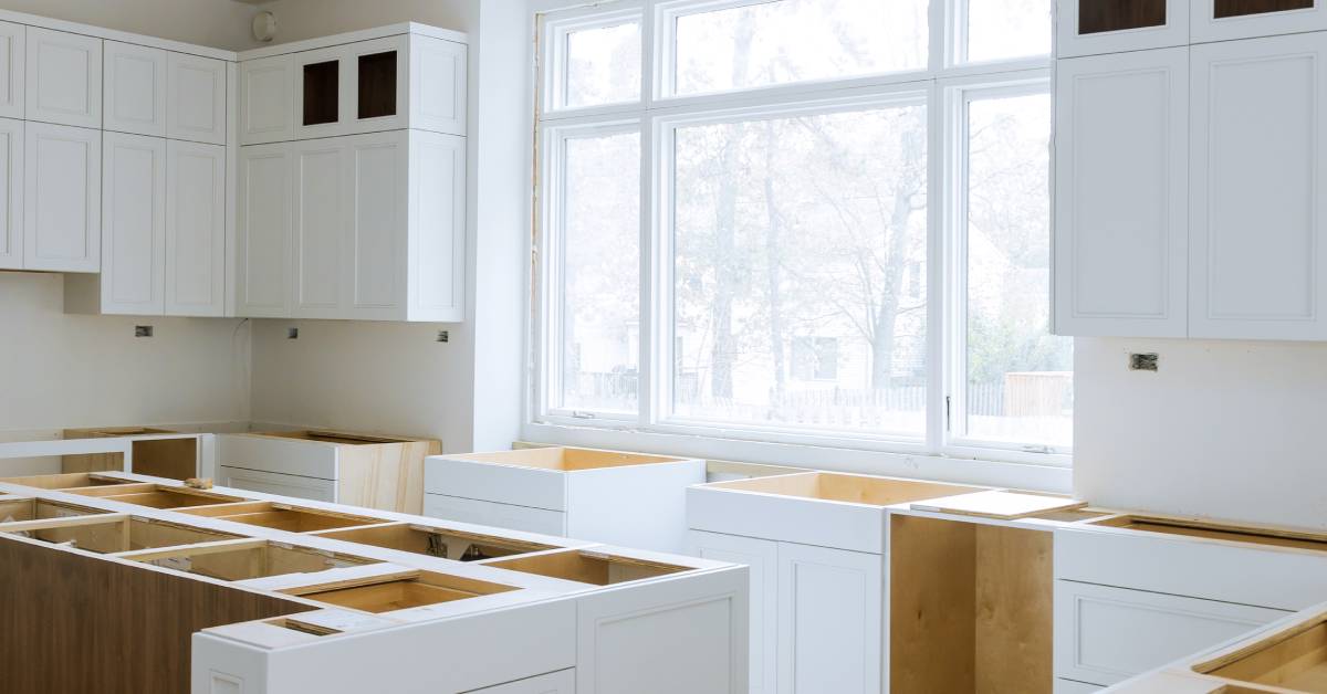 A large modern kitchen with white cabinetry in the middle of a renovation waiting for the countertop installation.