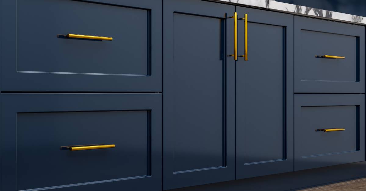 Closeup of dark navy blue cabinets and drawers with gold hardware and a marble countertop above them.